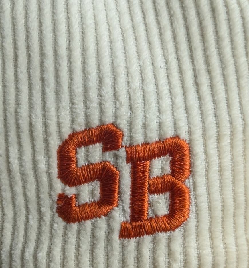 Official Sponsor Backed staggered collegiate SB monogram stitched in burnt cognac satin thread on cream wide-wale corduroy in Dallas, TX